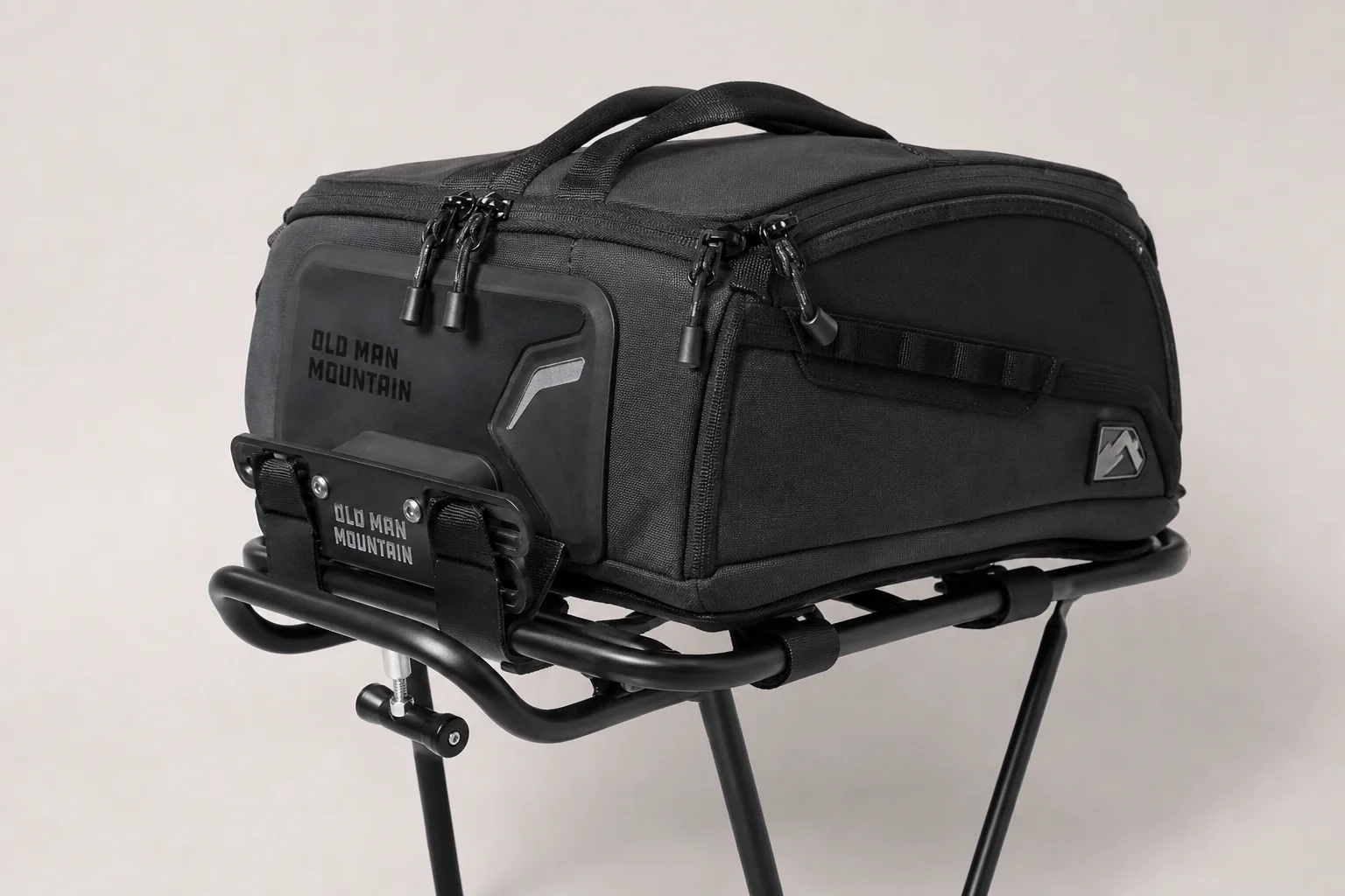 Fully loaded trail bike with Old Man Mountain racks and bags on neutral backdrop