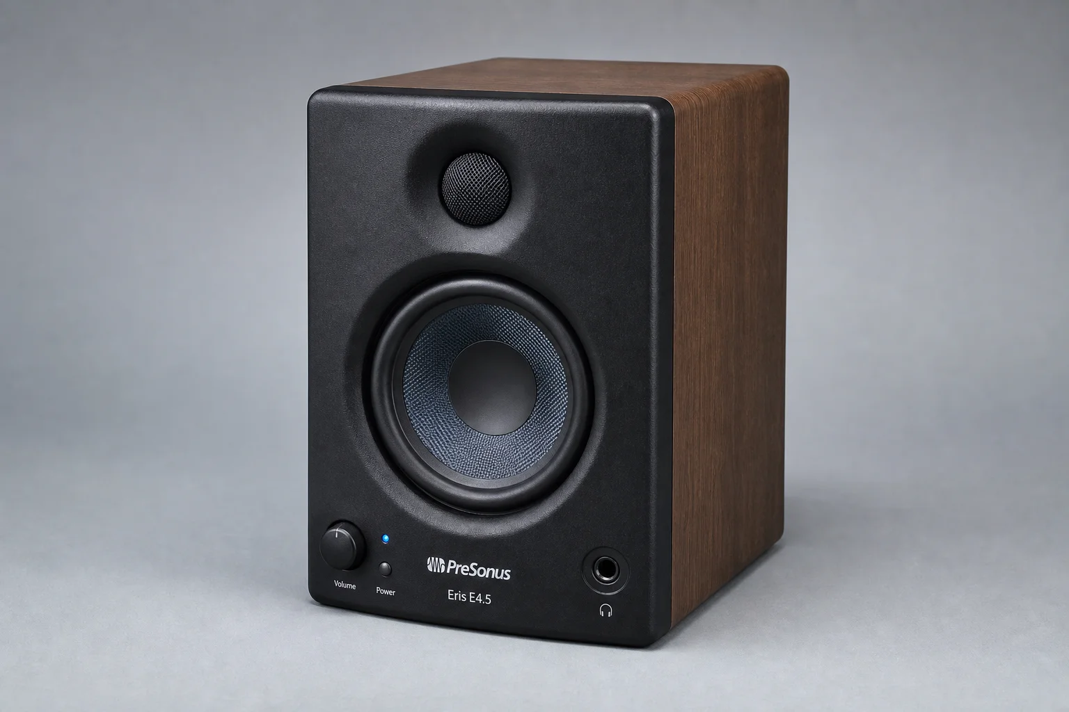 Five studio monitors arranged on concrete surface showing different sizes and designs