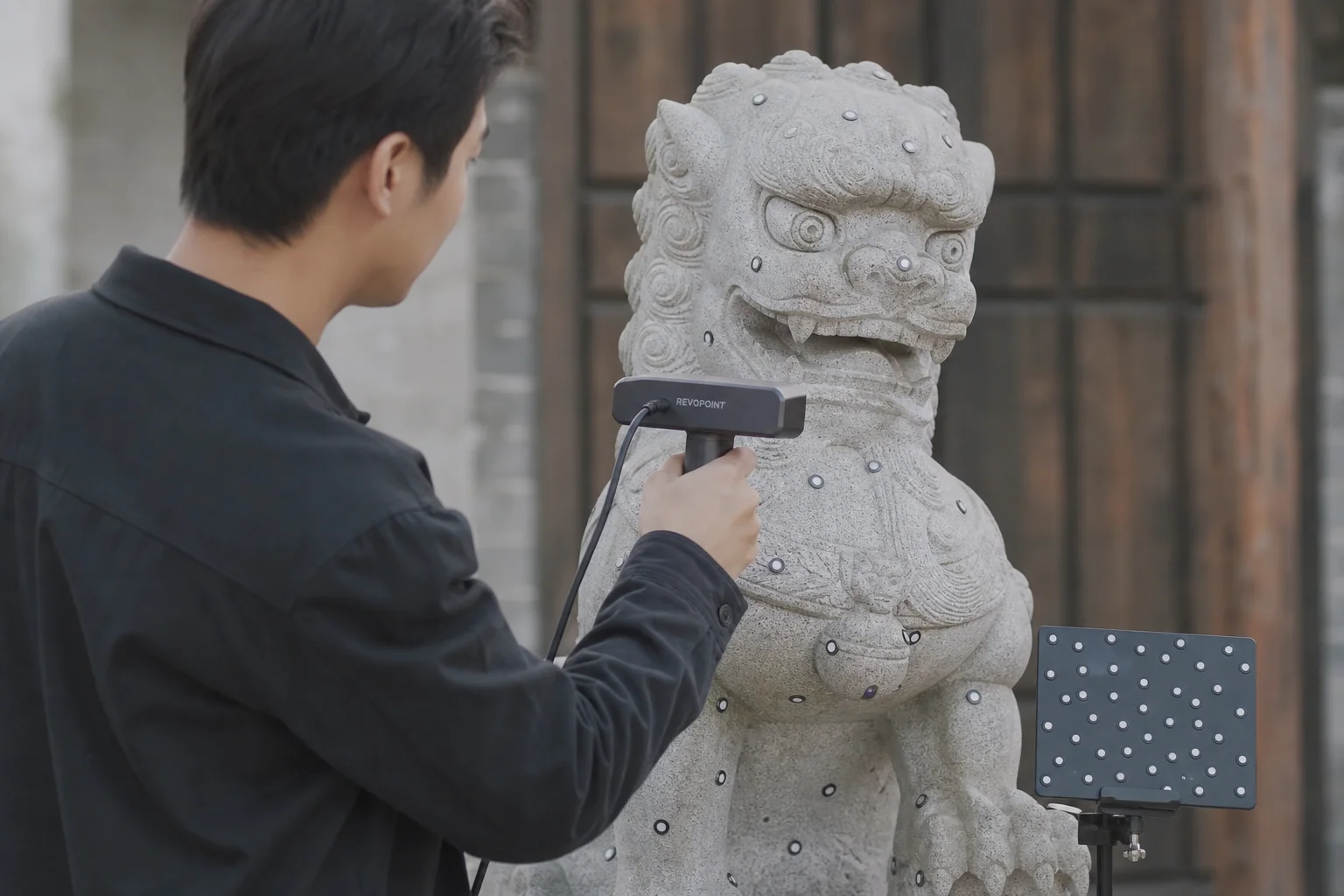 Handheld 3D scanner capturing details of a larger object outdoors