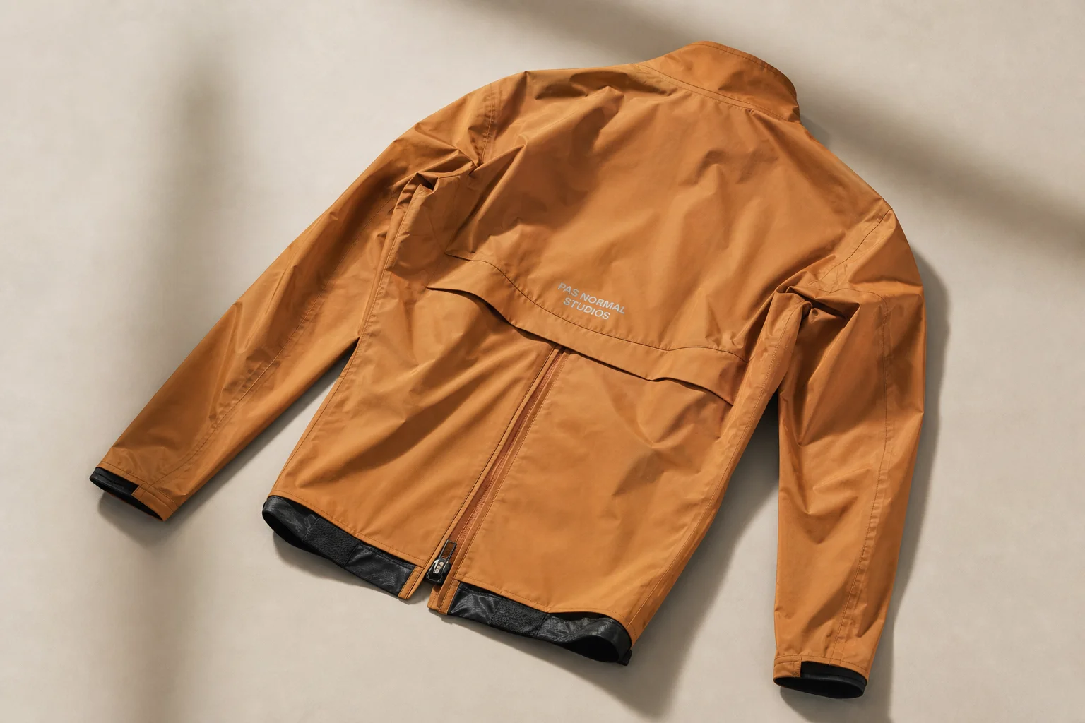 Five cycling rain jackets in various colors arranged on neutral backdrop