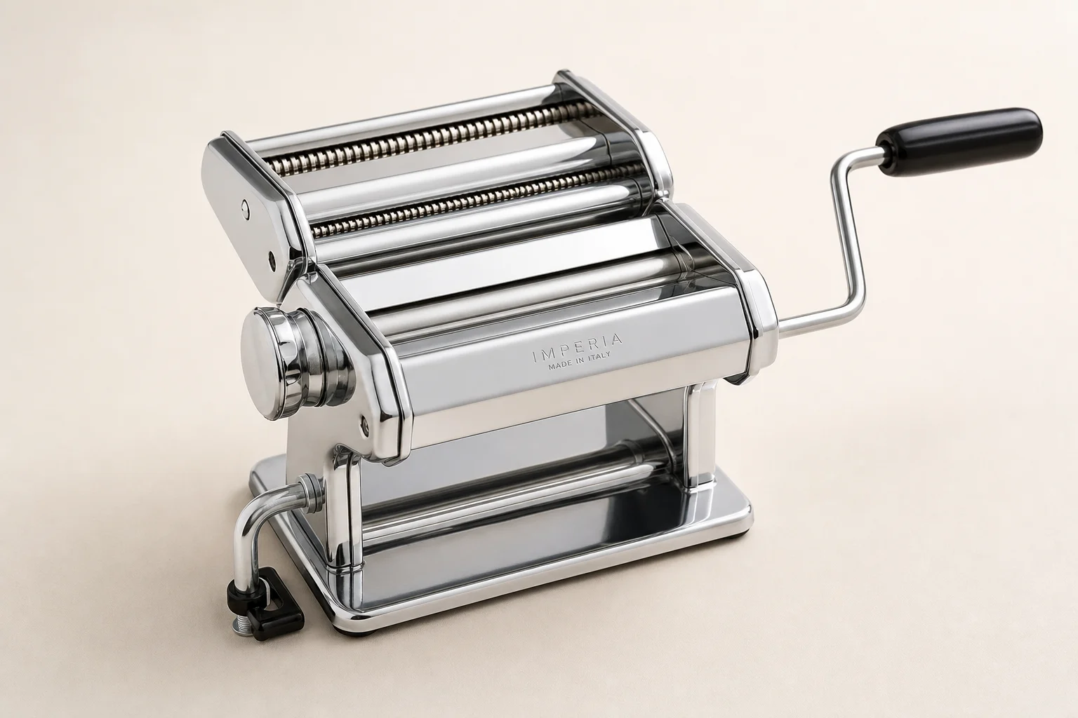 Five pasta makers arranged on wood surface including hand-crank and powered models