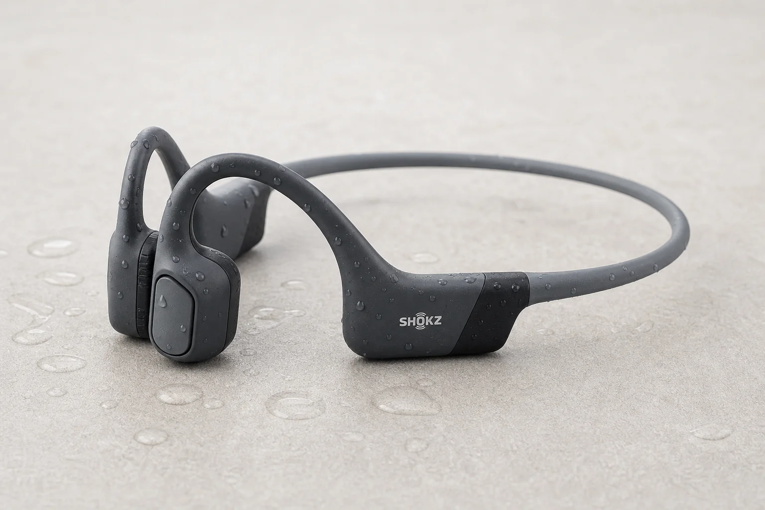 Six bone conduction headphones arranged on concrete surface showing different models and designs
