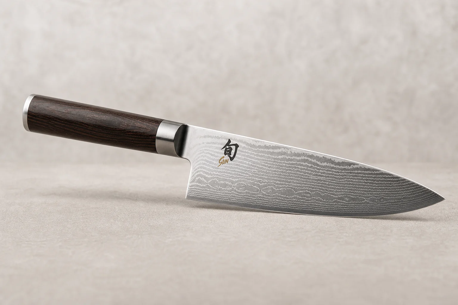 Collection of eight chef's knives arranged diagonally on concrete surface showing various styles and price points