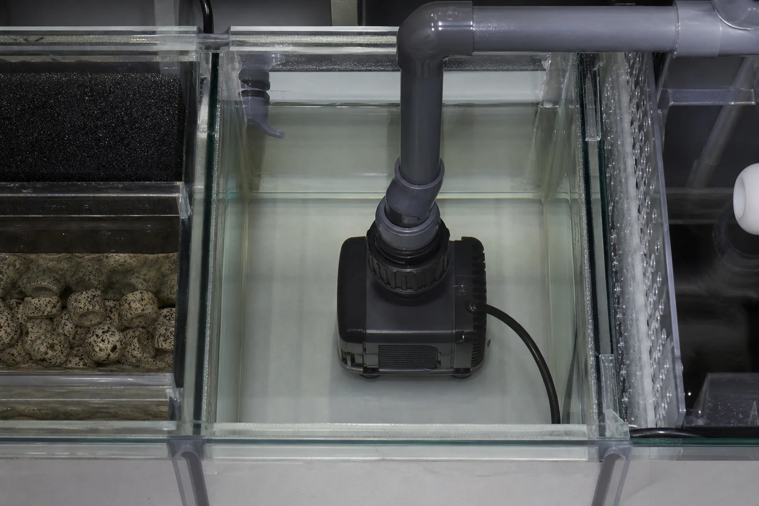 Reef aquarium tank with return pump installed in sump section