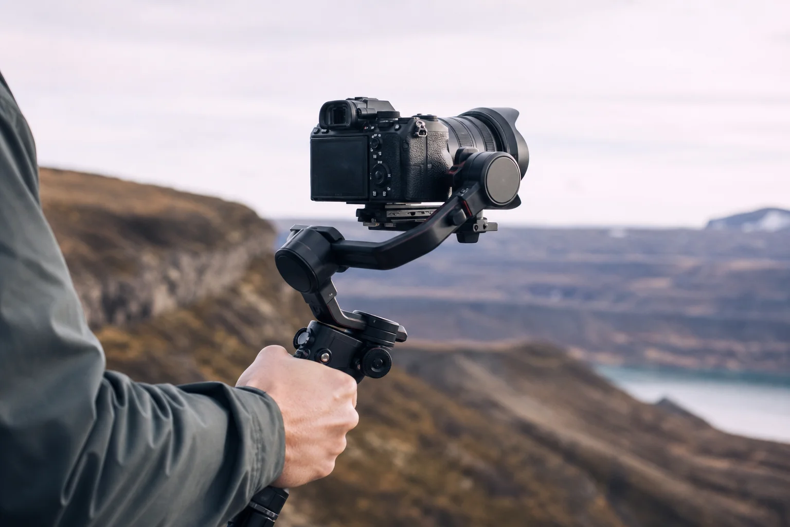 Videographer using a gimbal-mounted camera with wide-angle lens in outdoor setting