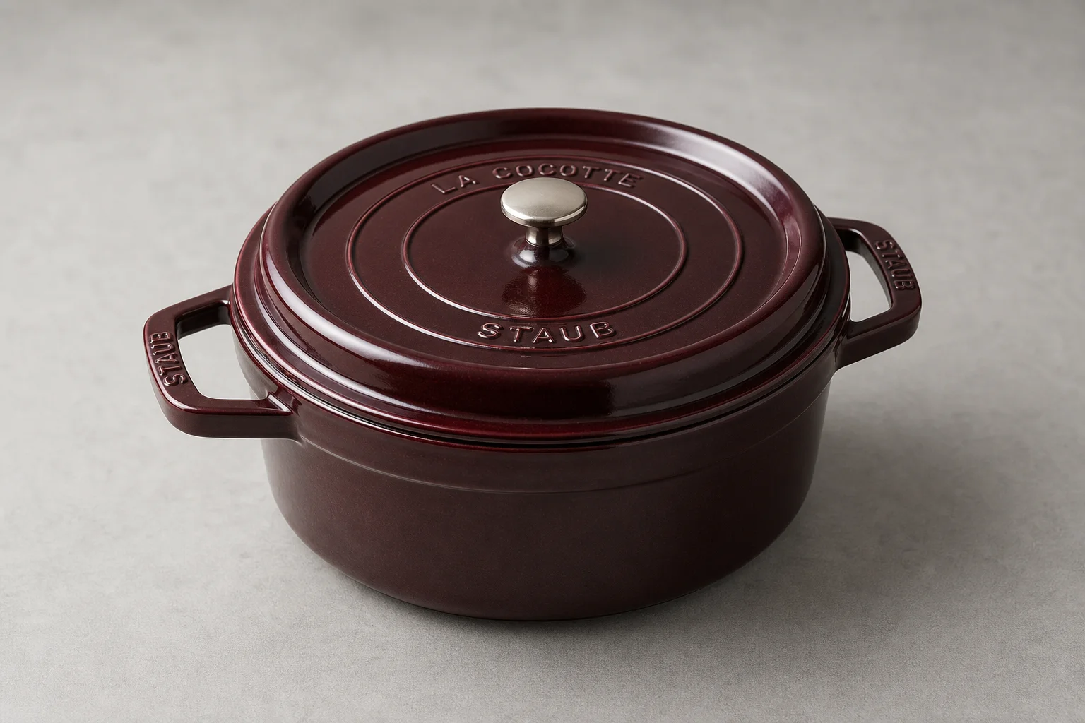 Three Dutch ovens in burgundy, cream, and red arranged on concrete surface