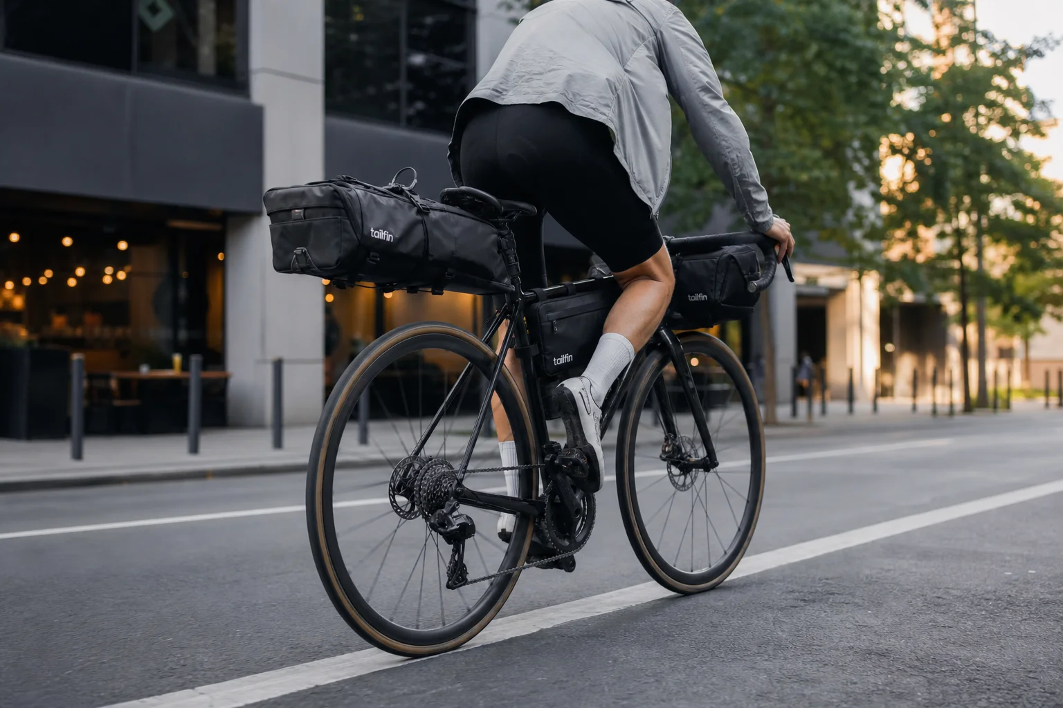 Cyclist commuting on a road bike loaded with Tailfin cargo bags in urban setting