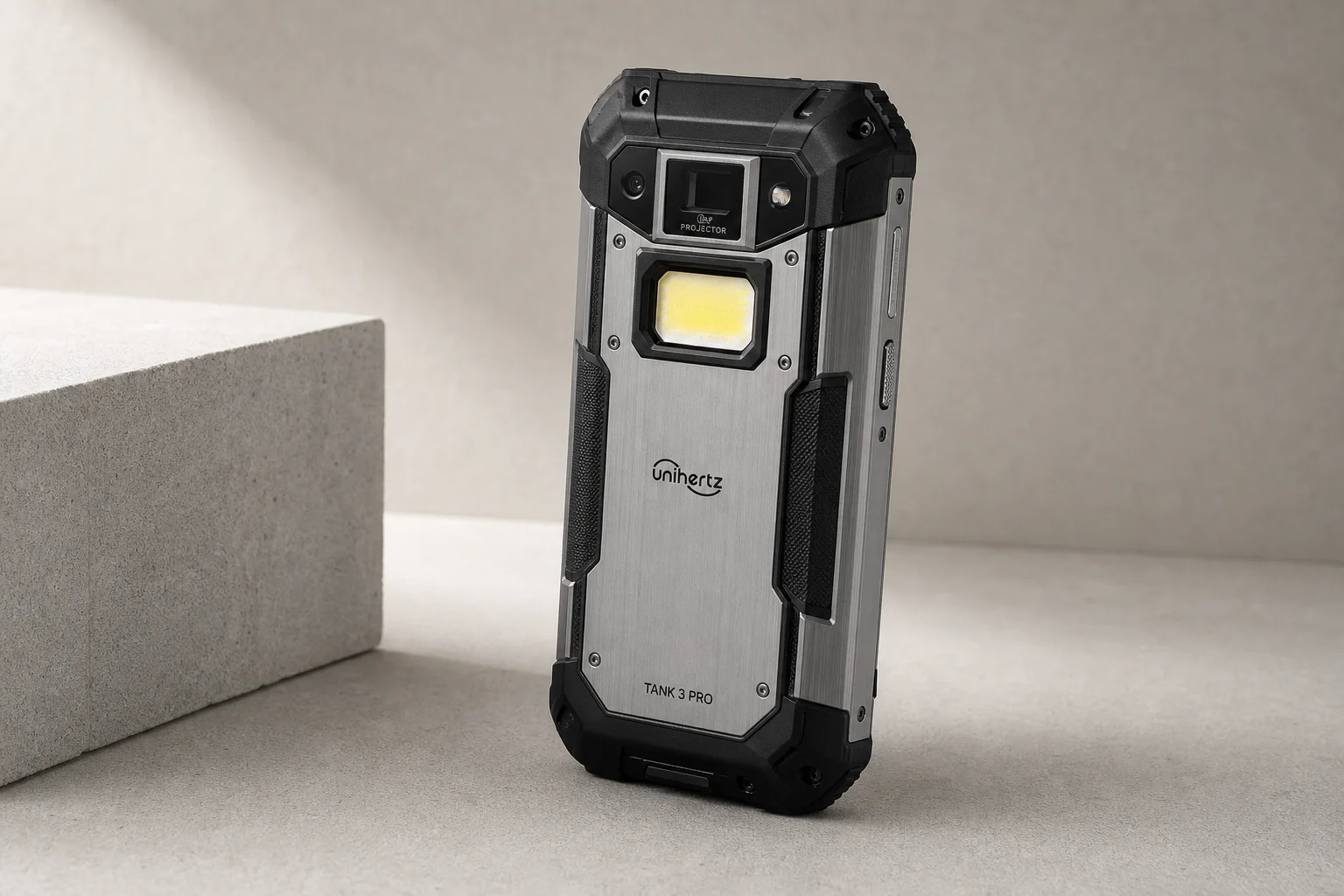 Smartphone robuste UniHertz Tank 3 Pro sur une surface en béton montrant l'objectif du projecteur et la lampe torche LED