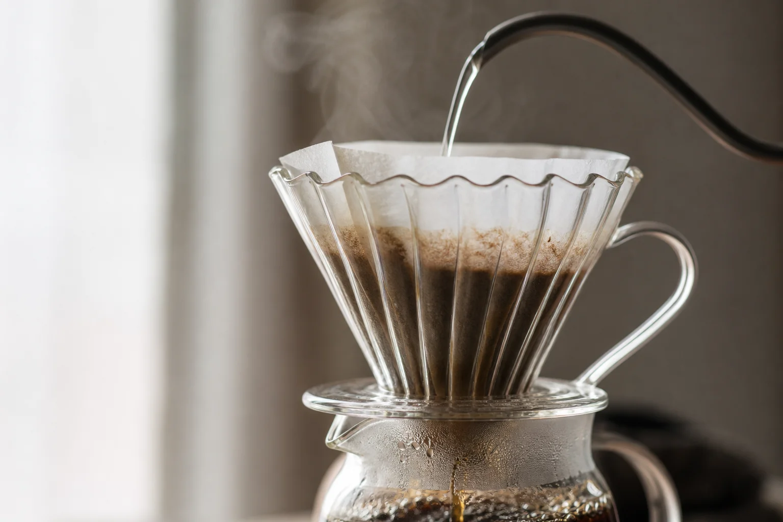 V60 dripper with water pouring through filter paper into glass carafe
