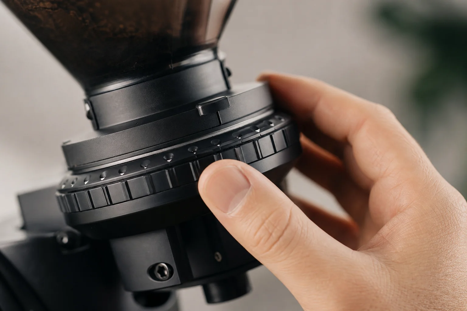 Hand adjusting stepped grind adjustment collar on coffee grinder