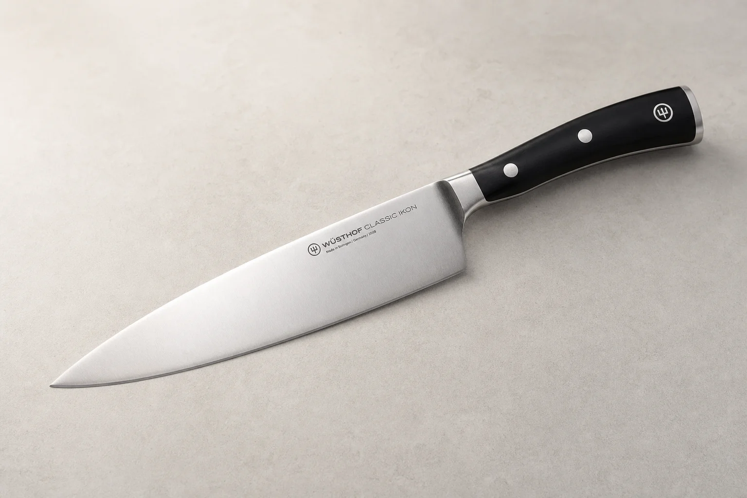 Collection of eight chef's knives arranged diagonally on concrete surface showing various styles and price points
