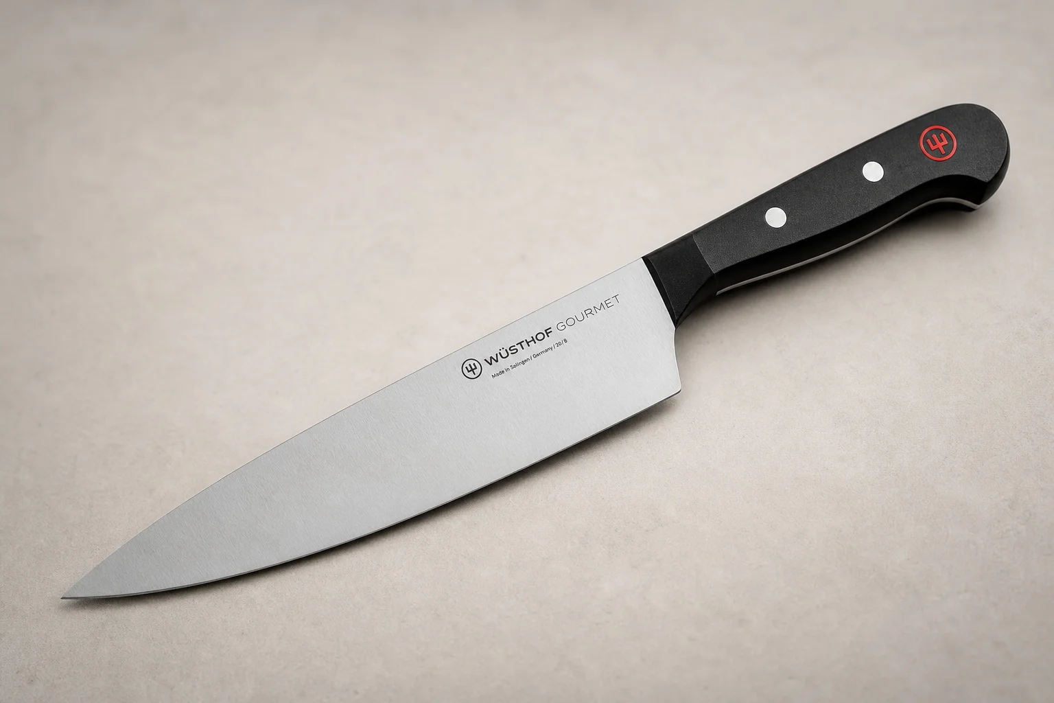 Collection of eight chef's knives arranged diagonally on concrete surface showing various styles and price points