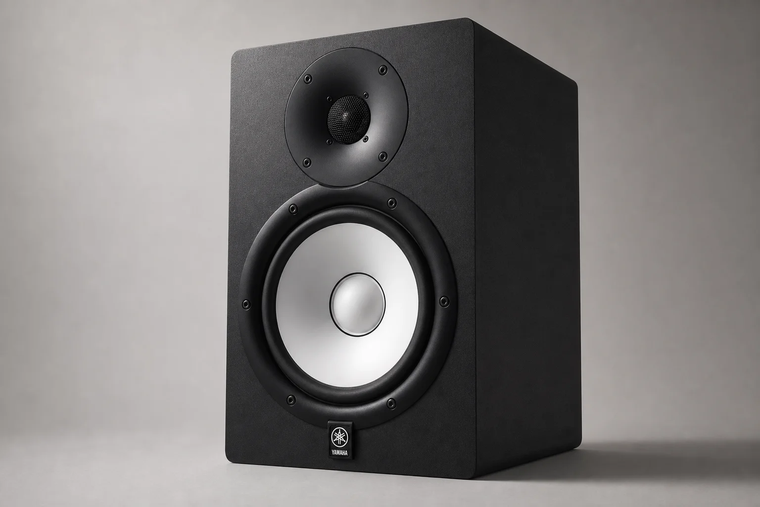 Five studio monitors arranged on concrete surface showing different sizes and designs