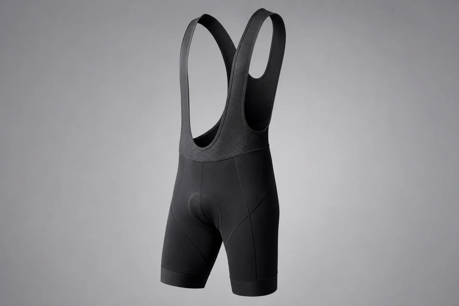 Cycling accessories flat-lay including carbon wheels, handlebar light, and bib shorts on concrete