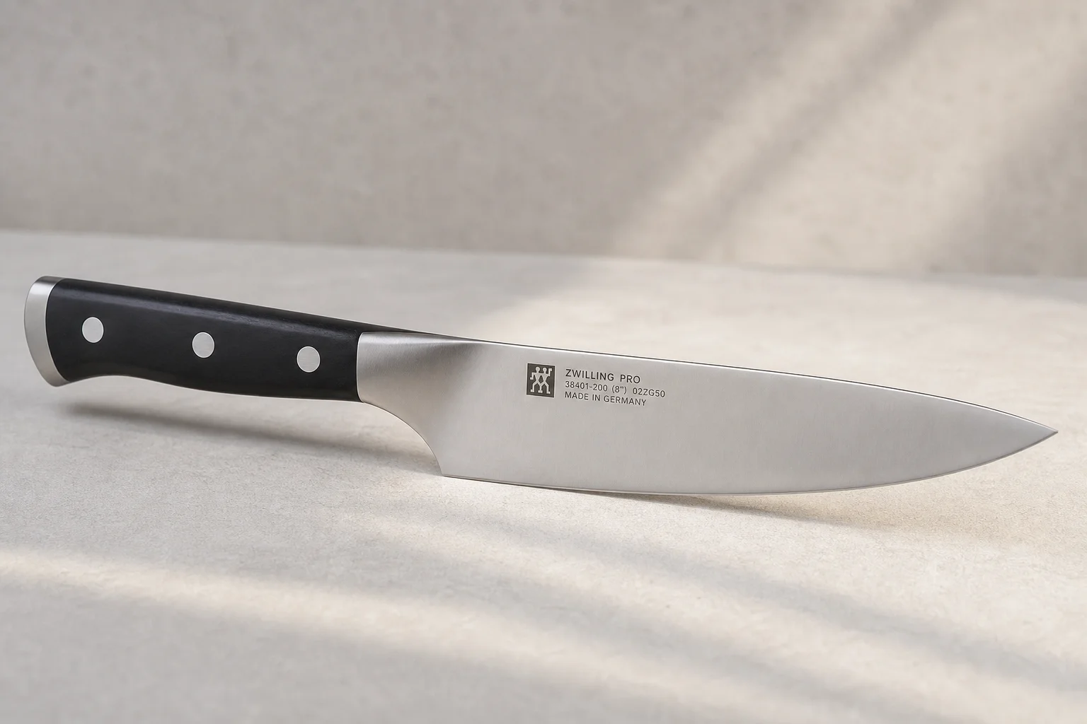Collection of eight chef's knives arranged diagonally on concrete surface showing various styles and price points